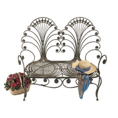 a metal bench with a hat on top of it next to flowers and a basket