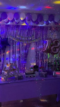 balloons and streamers are hanging from the ceiling in front of a table with cake