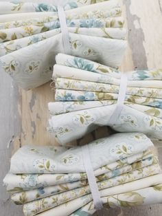 several pieces of white fabric with blue and green flowers are stacked on top of each other