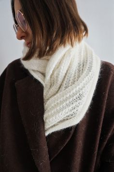 a woman wearing a brown coat and white knitted cowl neck scarf on her shoulder