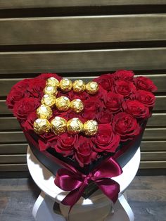 a heart shaped box filled with red roses and chocolates on top of a table