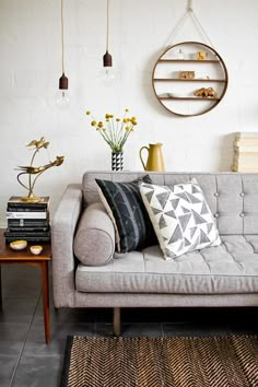 a living room with a couch, table and vases on the wall next to it