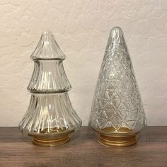 two clear glass vases sitting on top of a wooden table next to each other