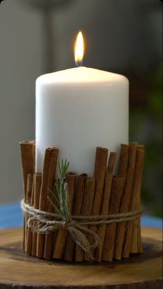 a white candle with cinnamon sticks wrapped around it