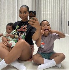 a woman taking a selfie with two small children in front of her on the phone