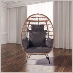 a wicker swing chair with two pillows on it in front of a wooden floor