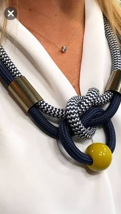 a close up of a woman wearing a white shirt and black and white rope necklace