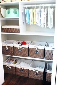 an organized closet with wicker baskets and baby clothes hanging on the wall above it