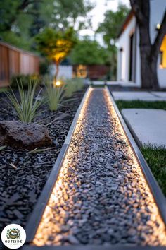 a long walkway is lit up by lights in the grass and rocks on the ground