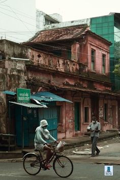 an old man riding a bike down the street with another man walking by behind him