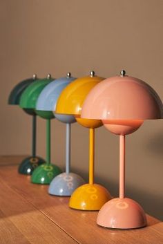 four different colored lamps are lined up on a wooden table with one lamp turned upside down