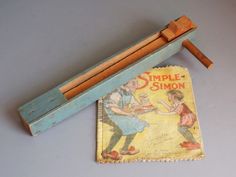 an old matchbox with a wooden stick sticking out of it's side next to a small children's book