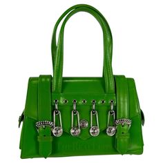 Presenting a fabulous bright green Gianni Versace safety pin mini bag, designed by Gianni Versace. A legendary creation from Gianni Versace's S/S 1994 collection, forever intertwined with Elizabeth Hurley's iconic 'Safety Pin' dress. This petite bag takes center stage with its striking silver metal Versace safety pins and Medusa logo. Adorned with two silver buckles, double magnetic closures, and delicate Versace Medusa reliefs, this bag is crafted from bright green leather. Its thoughtful design includes side pockets secured by Medusa closures and protective feet, ensuring a perfect balance of fashion and functionality. Approximate measurements: Height: 5.5" Width: 8.5" Depth: 3" Handle Drop: 5" Green Bag Outfit, Versace Safety Pin, Luxe Handbags, Pin Bag, Versace Bag, Versace Vintage, Vintage Versace, Elizabeth Hurley, Versace Bags