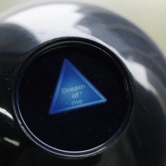 a close up of a button on a black object with a blue triangle and the words dream of me