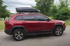 a red jeep is parked on the side of the road with its luggage strapped to it's roof