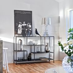 a living room filled with furniture and a painting on top of a shelf next to a window