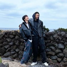 two men standing next to each other near rocks