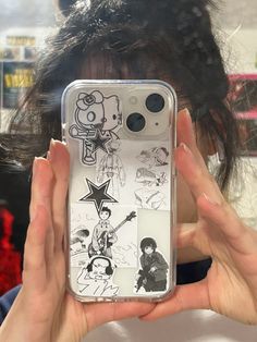 a person holding up a cell phone case with cartoon drawings on the back of it