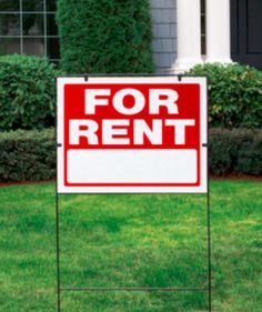 a red and white for rent sign in front of a house with bushes on the lawn