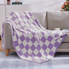 a purple and white checkered blanket sitting on top of a couch next to a christmas tree