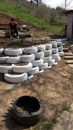 several tires stacked on top of each other in front of a man sitting on a bench