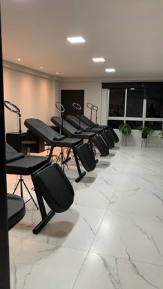 a row of black chairs sitting next to each other on top of a white floor