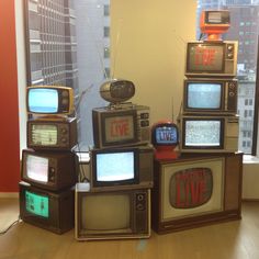 five old tvs stacked on top of each other in front of a large window