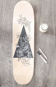 a skateboard sitting on top of a wooden floor next to some markers and pens