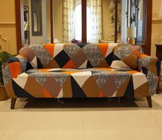 an orange and black couch sitting on top of a white floor next to a mirror