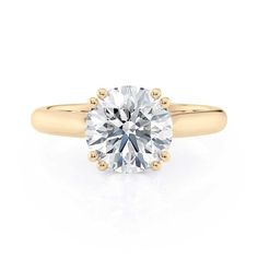 a yellow gold engagement ring with a round cut diamond in the center, on a white background