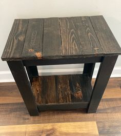 a small wooden table sitting on top of a hard wood floor next to a wall