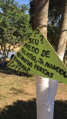 a yellow sign that is on the side of a white pole in front of some trees