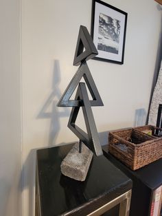 a metal sculpture sitting on top of a black table next to a basket and framed photograph