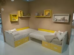 a room with two beds and yellow shelves