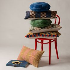 a stack of pillows sitting on top of a red chair next to a blue book