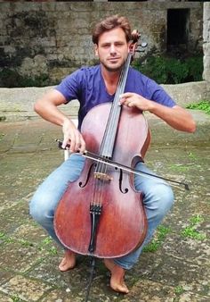 a man sitting on the ground holding an instrument