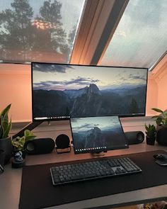 a desk with a computer monitor, keyboard and mouse on it in front of a window