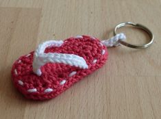 a red and white crocheted flip flop keychain sitting on top of a wooden table