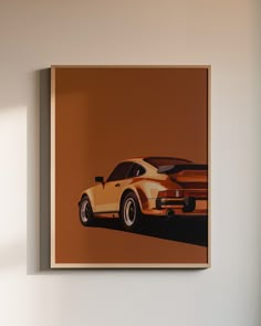 an orange and white car is on the wall next to a brown framed photograph in a room