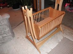 a wooden baby crib sitting on top of a floor next to a potted plant