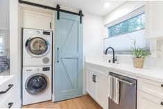 a washer and dryer in a white kitchen with blue door leading to the laundry room