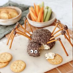 a spider made out of crackers sitting on top of a white plate next to some carrots