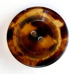 a brown and black object with two holes in the center on a white surface,