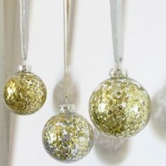 three gold and silver ornaments hanging from a white wall with snow flakes on them