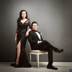 a man and woman in formal wear posing for a photo with one leg on a chair