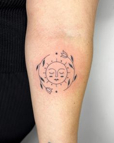 a woman's arm with a tattoo on it that has an image of a sun and leaves