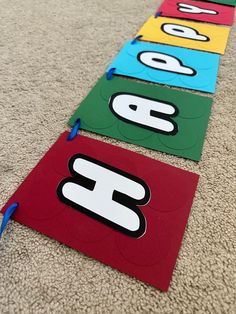 three colorful paper signs on the floor with blue string attached to them and two are numbered in different colors