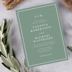 the wedding stationery is laid out on a table with greenery and wood slices