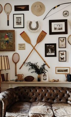 a couch sitting in front of a wall covered with pictures and paddles on it