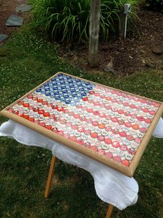 an american flag made out of soda cans on top of a table in the grass